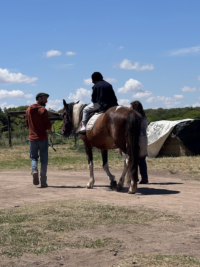 Paciente montando a caballo con instructor guiando la sesión